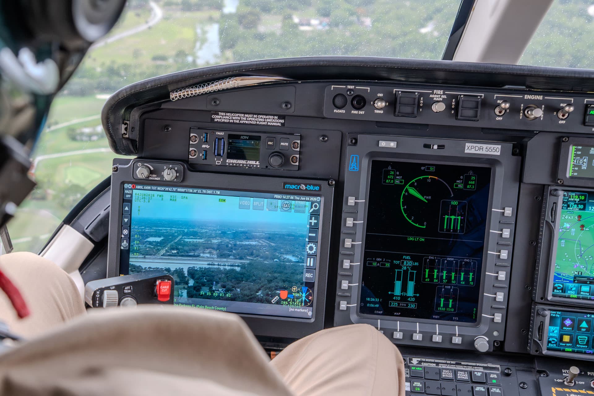 Law-enforcement helicopter instrument panel in flight, a Macro-Blue display at centre showing an EO/IR moving-map feed of the patrol area alongside the engine and navigation displays